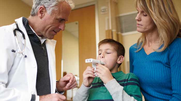 profesionist din domeniul sănătăţii ajutând un copil să utilizeze un produs pentru tratarea astmului