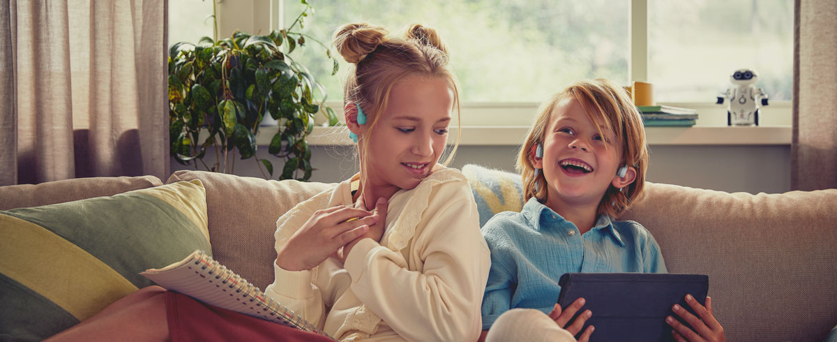 Copii bucurându-se de un videoclip utilizând căştile Philips cu design deschis pentru copii