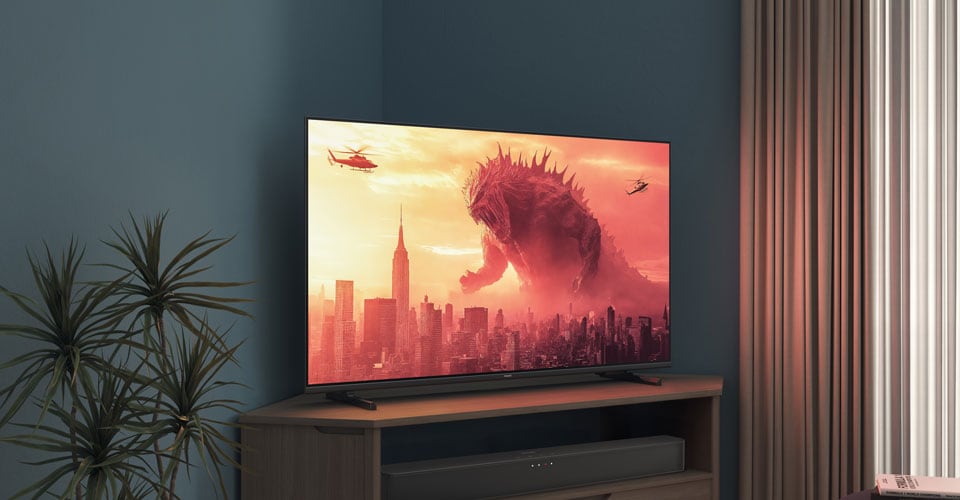Un televizor Philips pe un suport de colț afișează un film cu Godzilla