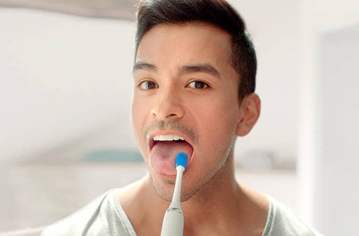 : Un bărbat își curăță limba folosind o perie specială Philips.